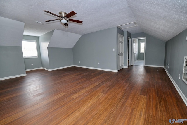 additional living space with a textured ceiling, vaulted ceiling, and dark hardwood / wood-style flooring