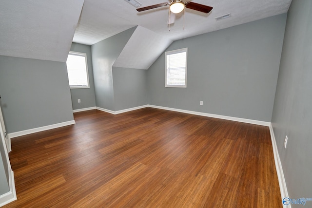 bonus room featuring lofted ceiling, a textured ceiling, a healthy amount of sunlight, and dark hardwood / wood-style flooring