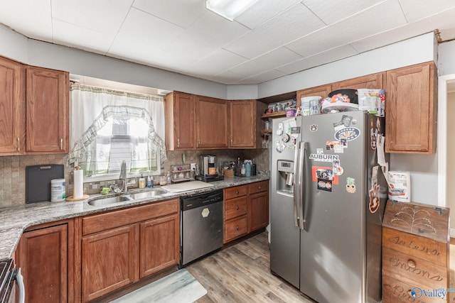 kitchen featuring stainless steel appliances, sink, decorative backsplash, and light hardwood / wood-style flooring