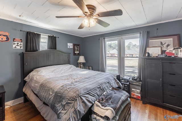 bedroom with multiple windows, hardwood / wood-style floors, crown molding, and ceiling fan