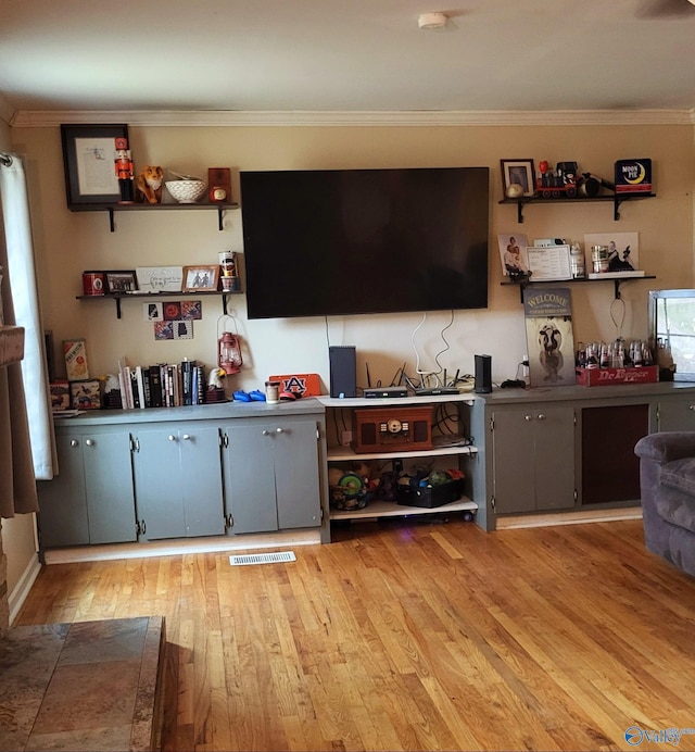 bar with ornamental molding, light hardwood / wood-style floors, and gray cabinetry