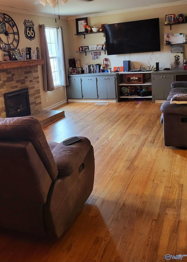 living room featuring crown molding, ceiling fan, a fireplace, and light hardwood / wood-style floors