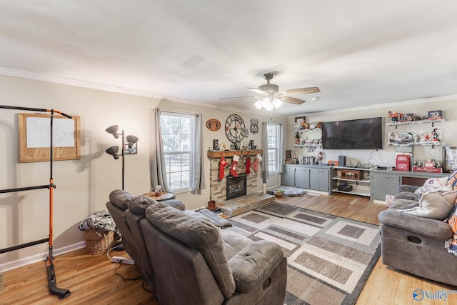 living room with hardwood / wood-style flooring, ornamental molding, ceiling fan, and a fireplace