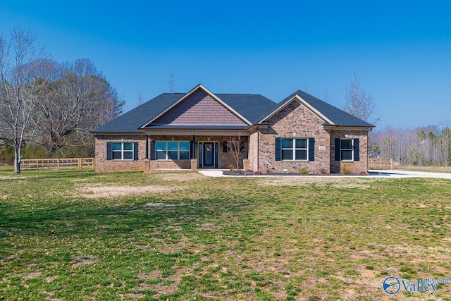 craftsman-style home with brick siding, a front yard, and fence