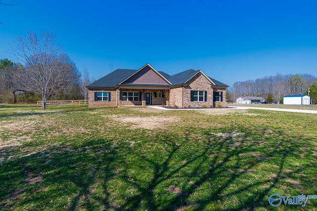 view of front of house with brick siding, a front yard, and fence