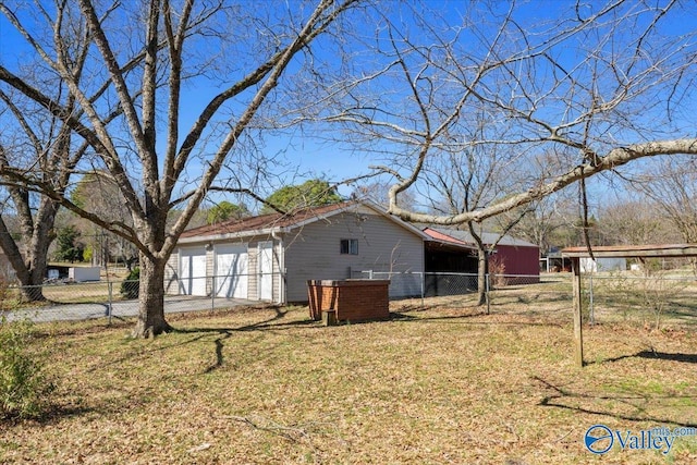 view of side of home with a garage, fence, and a lawn