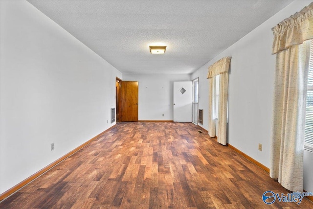 unfurnished bedroom with visible vents, a textured ceiling, baseboards, and wood finished floors