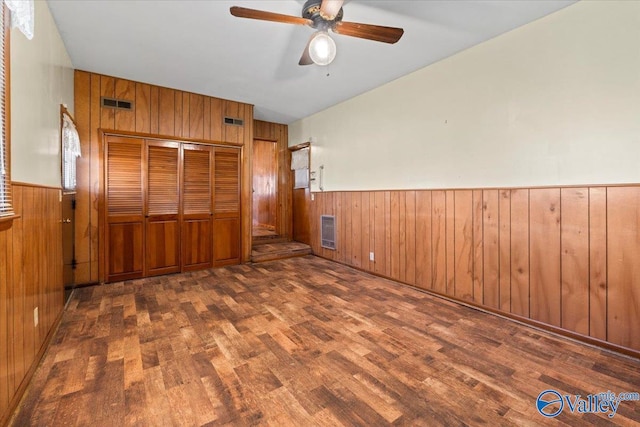 unfurnished bedroom featuring visible vents, wainscoting, wood finished floors, heating unit, and wood walls