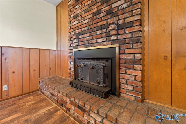 details featuring wood walls, a fireplace, wood finished floors, and wainscoting