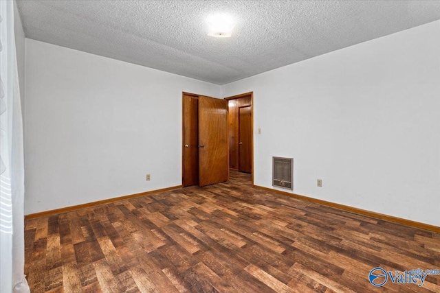 unfurnished room featuring heating unit, a textured ceiling, baseboards, and wood finished floors