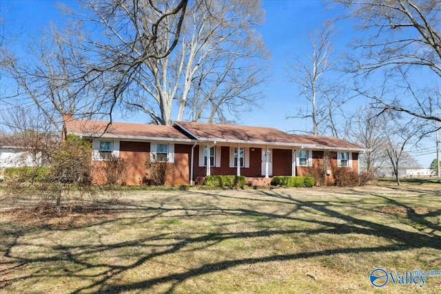 ranch-style home with a porch, a front yard, brick siding, and a chimney