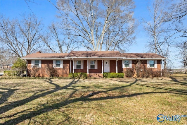 ranch-style home featuring brick siding, a chimney, and a front yard