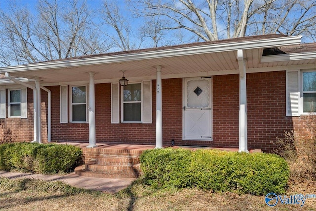 property entrance with a porch and brick siding