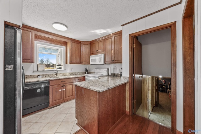 kitchen with sink, white appliances, light stone countertops, a textured ceiling, and kitchen peninsula