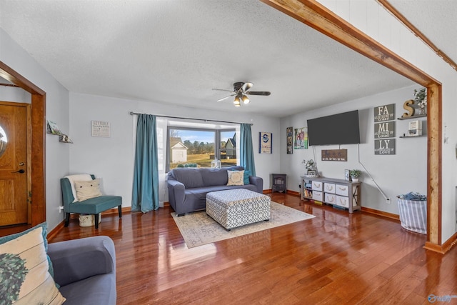 living room with hardwood / wood-style flooring, ceiling fan, and a textured ceiling