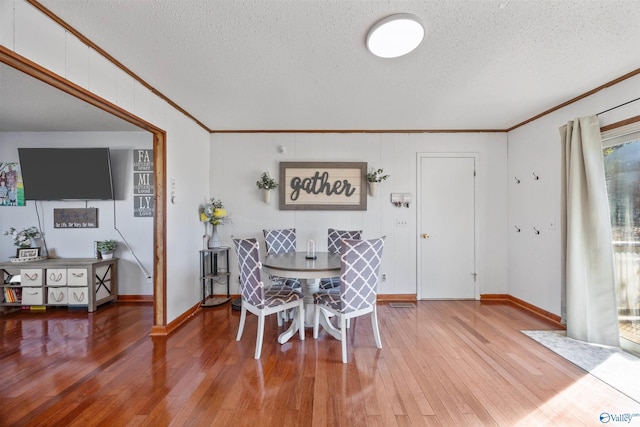 dining space with ornamental molding, hardwood / wood-style floors, and a textured ceiling