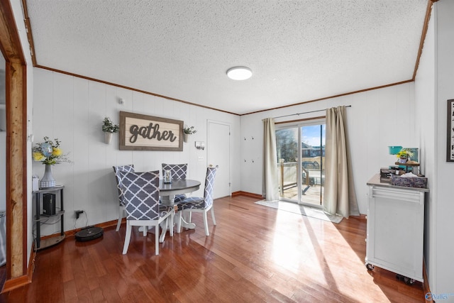 dining area with ornamental molding, hardwood / wood-style floors, and a textured ceiling