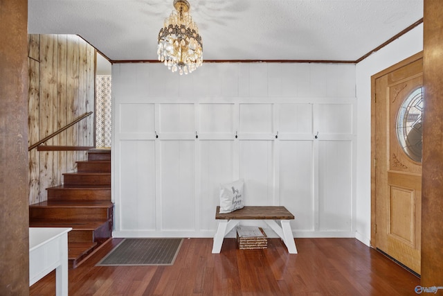 foyer entrance featuring dark hardwood / wood-style flooring, crown molding, a textured ceiling, and an inviting chandelier