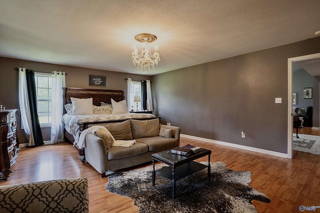 208 Burgess Ave, Rainsville, AL 35986 - bedroom with light wood-style floors, a chandelier, baseboards, and a textured ceiling