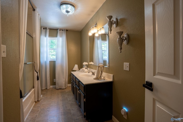208 Burgess Ave, Rainsville, AL 35986 - bathroom with plenty of natural light, double vanity, a textured wall, combined bath / shower with glass door, and baseboards
