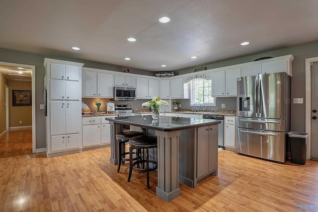 208 Burgess Ave, Rainsville, AL 35986 - kitchen featuring stainless steel appliances, white cabinetry, light wood-style flooring, a kitchen bar, and recessed lighting