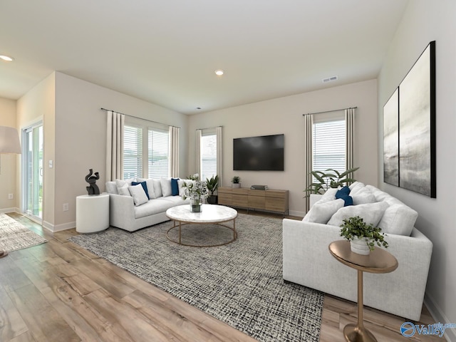 living area featuring wood finished floors, healthy amount of natural light, recessed lighting, and baseboards