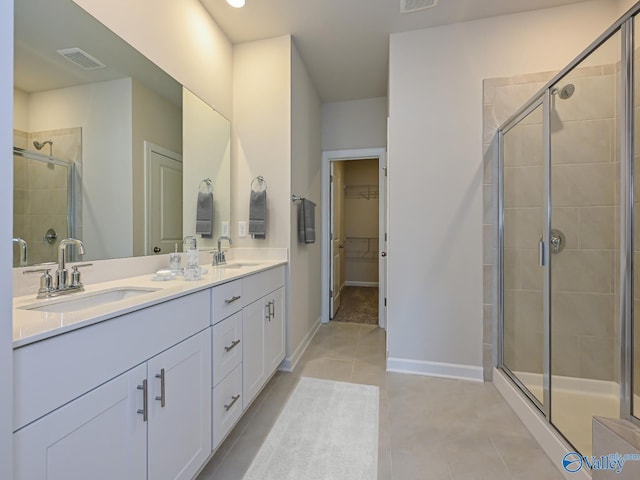 bathroom with a shower stall, tile patterned flooring, double vanity, and a spacious closet