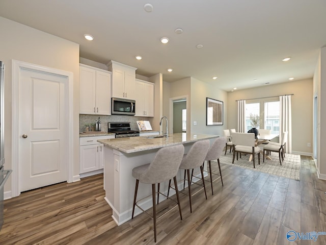 kitchen featuring stainless steel microwave, range, a sink, dark wood-style floors, and recessed lighting