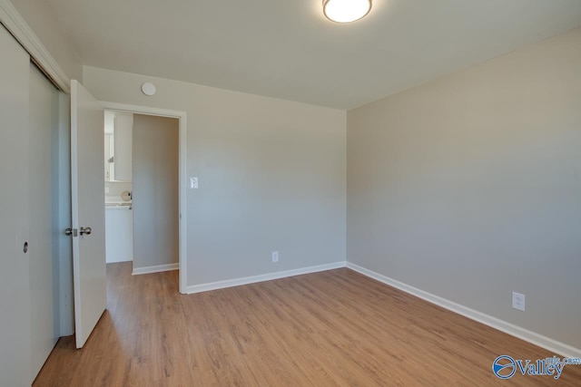 unfurnished bedroom with a closet, baseboards, and light wood finished floors