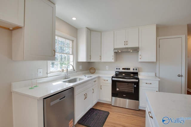 kitchen featuring stainless steel appliances, light countertops, a sink, and under cabinet range hood