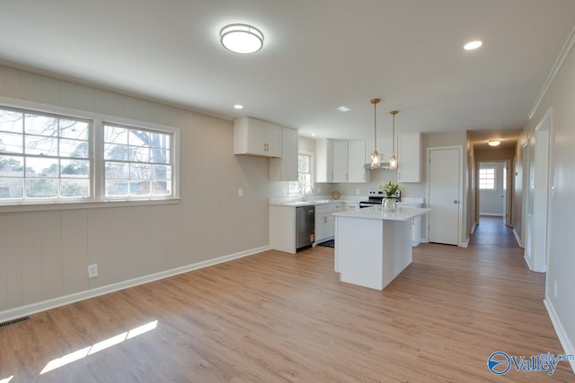 kitchen featuring light countertops, appliances with stainless steel finishes, white cabinets, a sink, and light wood-type flooring