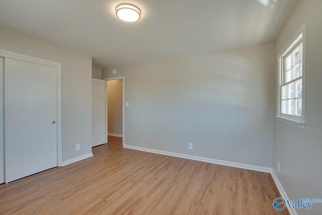 unfurnished bedroom featuring light wood finished floors, baseboards, and a closet