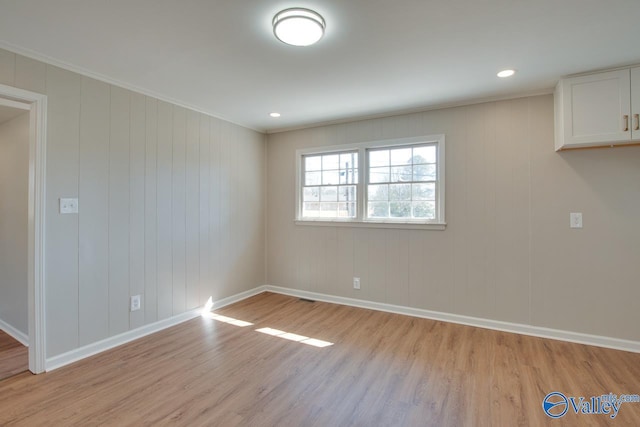 spare room featuring baseboards, crown molding, visible vents, and light wood finished floors