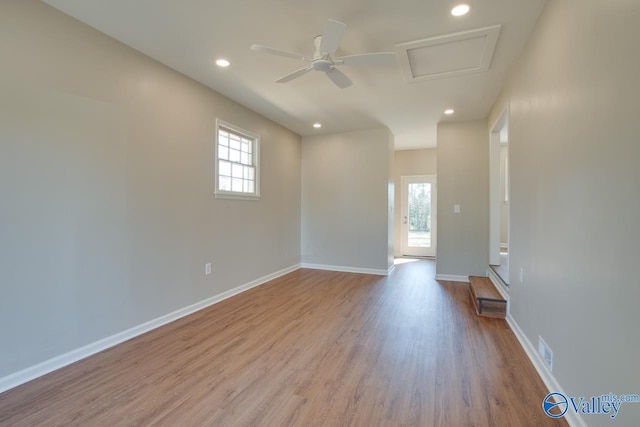 spare room featuring recessed lighting, wood finished floors, attic access, and baseboards