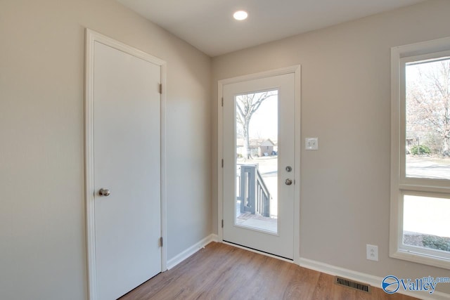 entryway with a healthy amount of sunlight, baseboards, visible vents, and wood finished floors