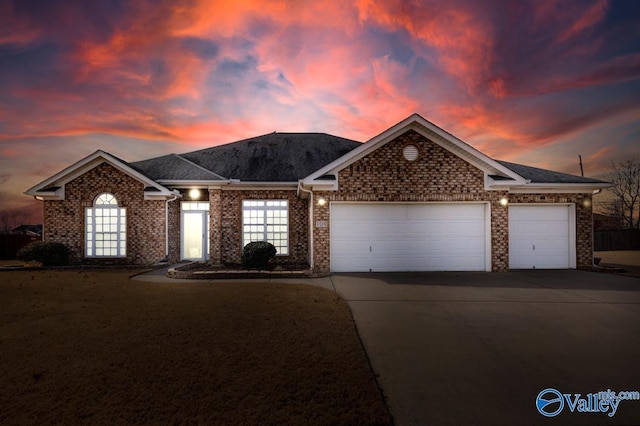 single story home featuring a garage, concrete driveway, and brick siding