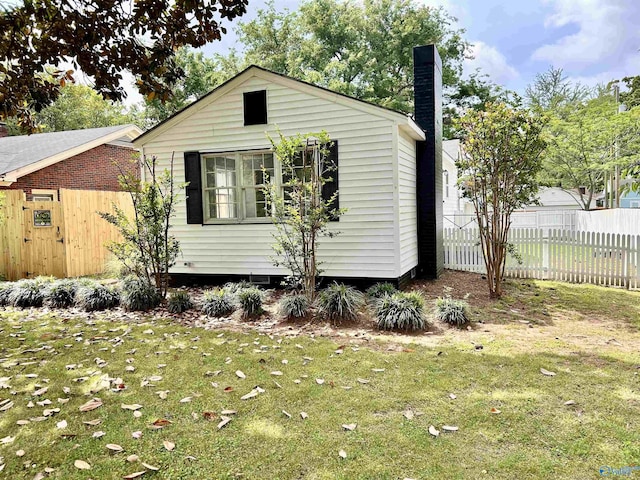 view of side of property featuring fence, a yard, and a chimney