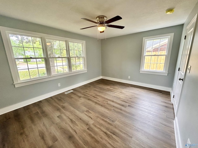 empty room featuring baseboards, a ceiling fan, wood finished floors, and visible vents