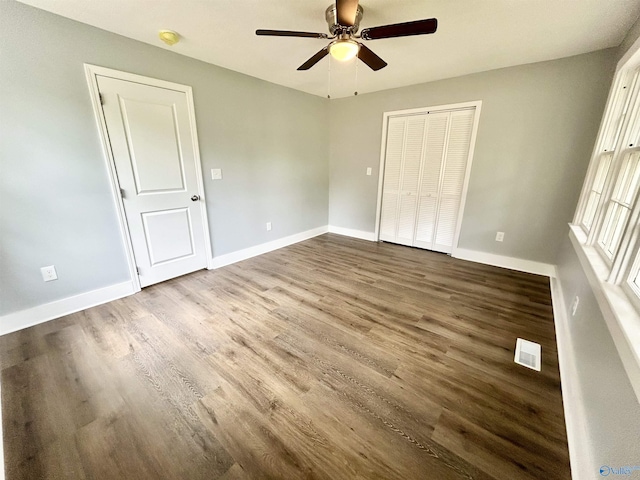 unfurnished bedroom with baseboards, visible vents, wood finished floors, and a closet