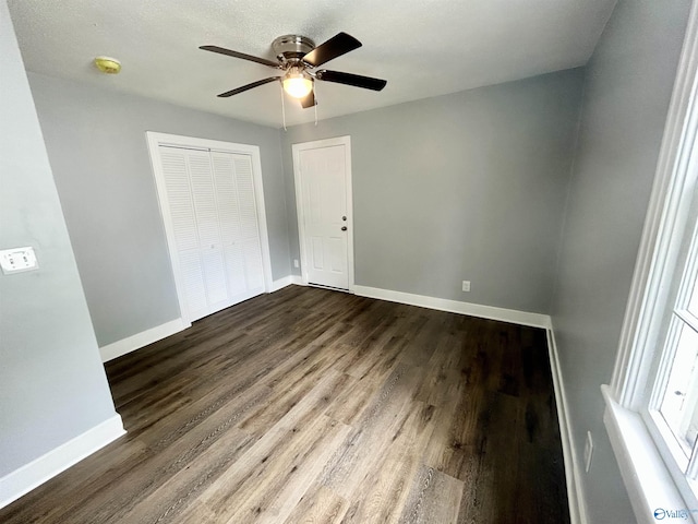 unfurnished bedroom with dark wood-style flooring, baseboards, ceiling fan, and a closet