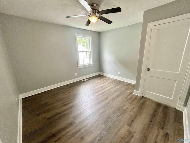 spare room with baseboards, ceiling fan, and dark wood finished floors