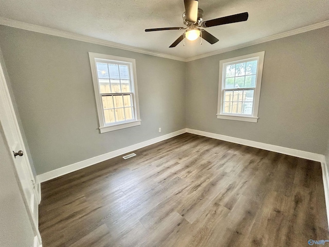empty room with crown molding, dark wood finished floors, and baseboards