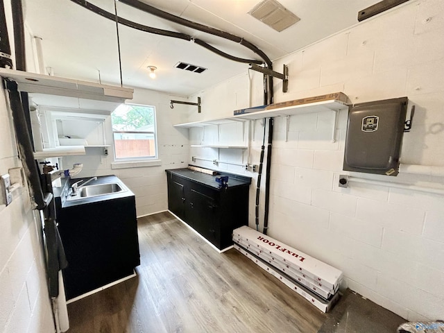 kitchen featuring concrete block wall, visible vents, a sink, and light wood-type flooring