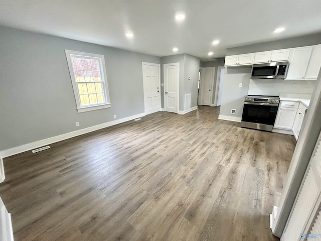 kitchen featuring stainless steel appliances, baseboards, white cabinetry, wood finished floors, and visible vents
