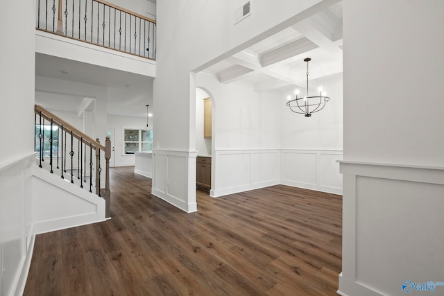 unfurnished dining area with coffered ceiling, beam ceiling, dark wood-type flooring, and an inviting chandelier