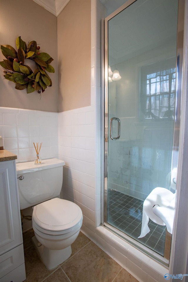 bathroom with a shower with door, tile walls, vanity, tile patterned floors, and toilet