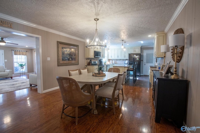 dining area featuring ornamental molding, dark wood-type flooring, ceiling fan with notable chandelier, and a textured ceiling