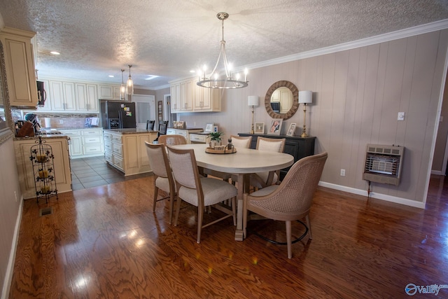 dining area featuring dark wood-type flooring, crown molding, a chandelier, and heating unit