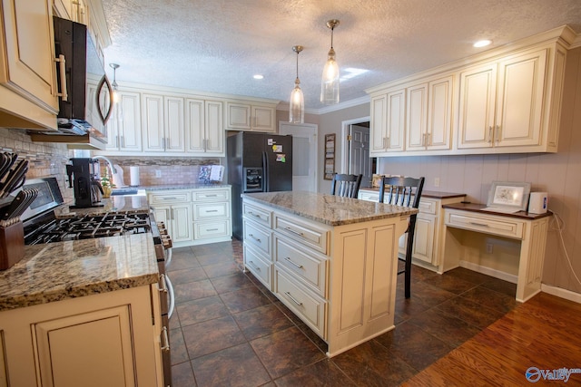 kitchen featuring black fridge with ice dispenser, gas stove, light stone counters, hanging light fixtures, and a kitchen island