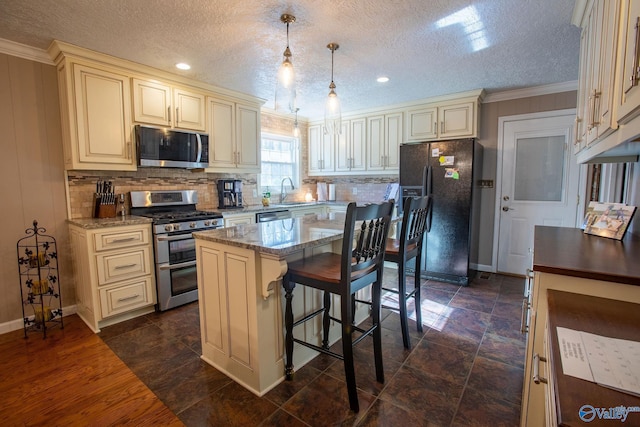 kitchen featuring decorative light fixtures, a center island, light stone counters, stainless steel appliances, and cream cabinetry